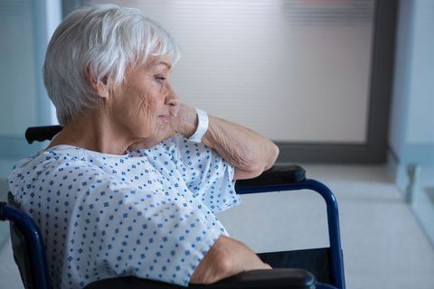 Senior Woman Resting in Wheelchair in Hospital Corridor