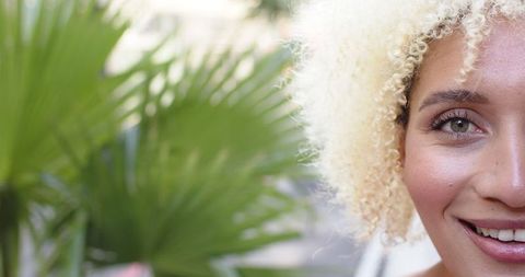 joyful young woman with curly blonde hair and vibrant green foliage - Download Free Stock Images Pikwizard.com
