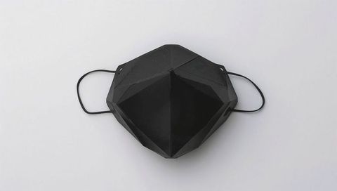 Black geometric faceted face mask lying on minimal white background for e-commerce