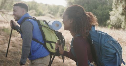 Happy Couple Hiking With Backpacks in Sunny Forest