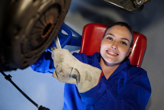 Portrait of female mechanic repairing a car at the repair garage