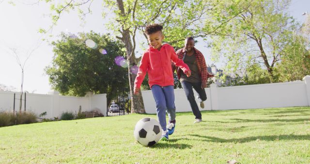 Happy african american father and his son playing football in garden - Download Free Stock Photos Pikwizard.com