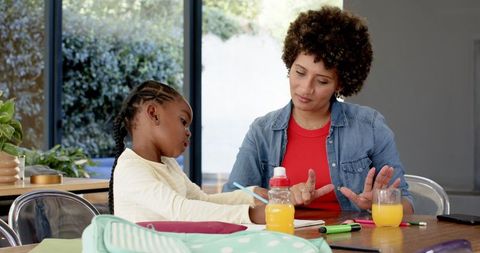 Mother and Daughter Bonding over Homework at Dining Table