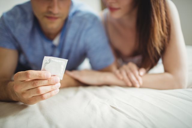 Close-up of couple with a condom on bed in the bedroom