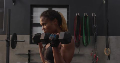 Strong African American Woman Exercising with Dumbbells in Gym