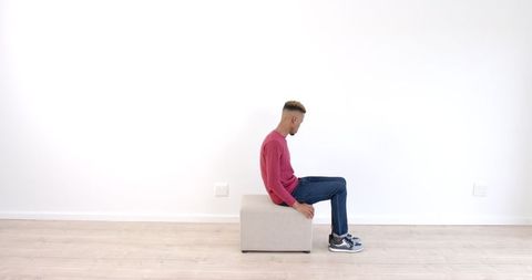Young Man Sitting on Ottoman in Thoughtful Contemplation