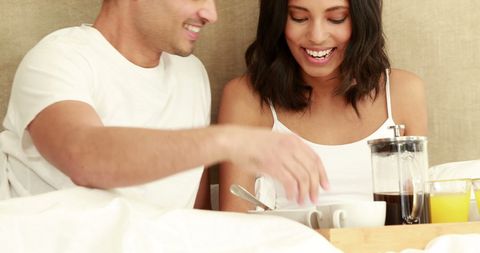 Couple Enjoying Relaxed Breakfast in Bed with Laughter