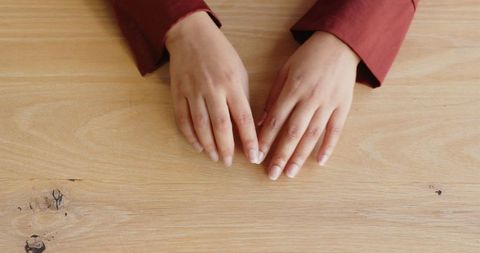 Hands with Red Sleeves Resting on Wooden Office Table