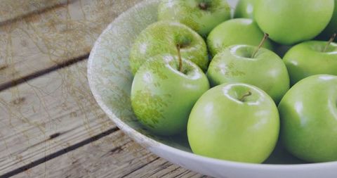 Bowl of Glossy Green Apples on Rustic Wooden Table