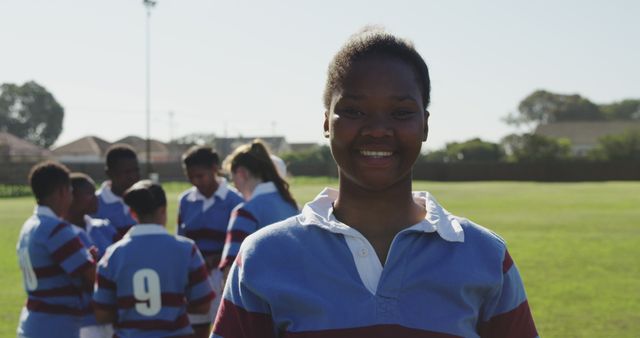 Young Athlete Smiling at Rugby Field, Team in Background - Download Free Stock Images Pikwizard.com