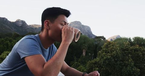 Man sipping beverage with scenic mountain view