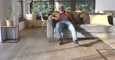 Senior Man Relaxing on Sofa with Tablet in Modern Living Room