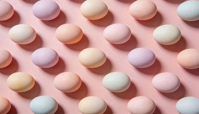Pastel easter eggs arranged in diagonal grid on pink background minimalist pattern soft shadows