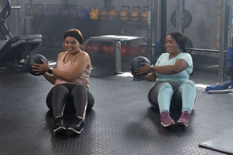 Diverse women smiling while working out with medicine balls on gym floor for core strength