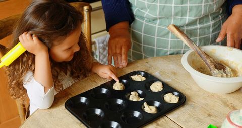 Child Baking Muffins with Family Member in Cozy Kitchen Setting