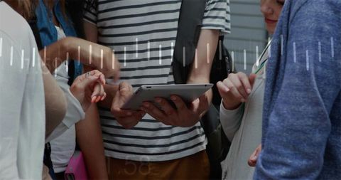College students sharing tablet, collaborating on campus with backpacks and earbuds