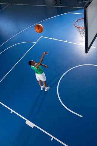Athletic woman perfecting basketball free-throw on blue court