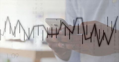 Holding smartphone viewing financial charts and analytics overlay for mobile trading