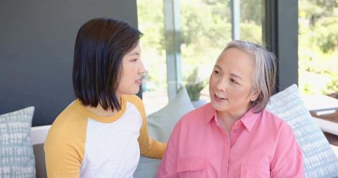 Adult Daughter Comforting Mother on Sunroom Sofa During Warm Family Conversation and Bonding Moment