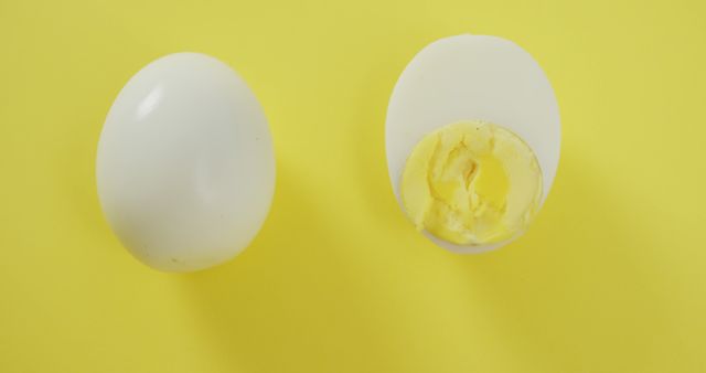 Whole and half boiled eggs placed on yellow background. Perfect for food blogs, cooking tutorials, nutritional guides, and healthy lifestyle websites highlighting breakfast options.