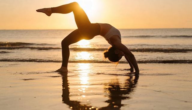 Golden hour beach yoga backbend with one-leg wheel pose and water reflection