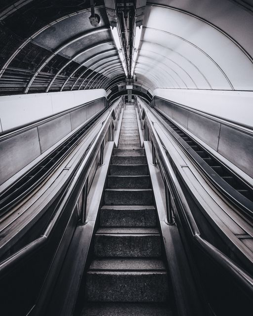 Futuristic-looking urban escalator view in a subway station. Includes symmetrical architecture and clean design. Perfect for travel, transportation, city life themes, and modern urban infrastructure concepts.