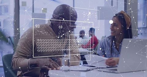 Colleagues collaborating over documents with digital data overlays and laptop in office