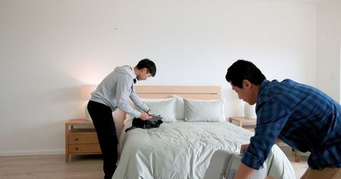 Father and Son Packing Suitcase Together on Bed