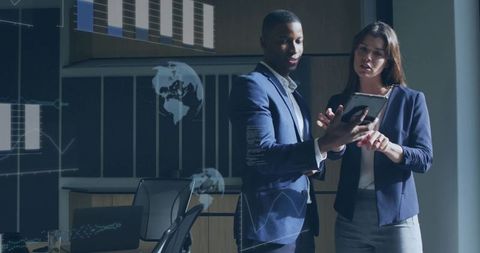 Business professionals collaborating over tablet with data visualizations in conference room