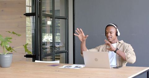 Man using laptop while wearing headphones in modern office environment