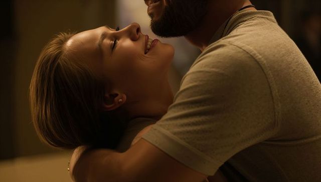 Embracing couple sharing intimate moment in warm low light, smiling and close