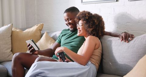 Casual Couple Playing Video Games on Couch Using Smartphone