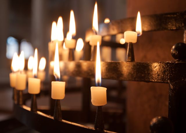 This image depicts a close-up view of lit candles in a church, casting a warm and serene light. Ideal for religious or spiritual content, articles on prayer and reflection, and materials needing meditative visual elements. Can be used to evoke a sense of peace, tradition, and worship.