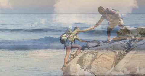 Hikers climbing rocky outcrop by ocean in adventurous scene