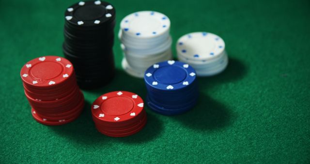Poker chips arranged on a green felt table create an atmosphere of a casino game in progress. This setup is ideal for use in articles and advertisements related to gambling, casino promotions, poker tournaments, or gaming strategies.