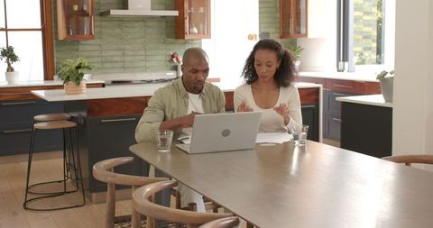 Diverse couple collaborating on laptop planning home project