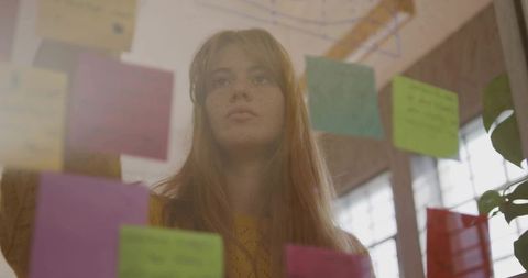 Creative Woman Analyzing Sticky Notes at Workplace