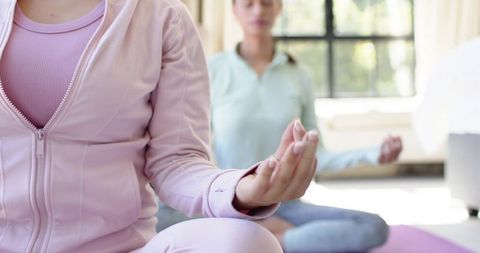 Women practicing meditation and breathwork on yoga mats in sunlit living room