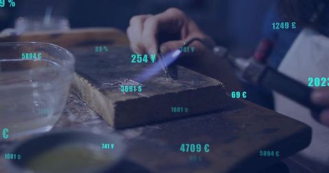 Craftsman Heating Metal with Torch on Workbench Showing Currency Symbols