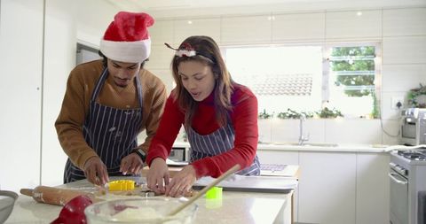 Couple baking Christmas cookies together in sunlit modern kitchen, festive holiday baking