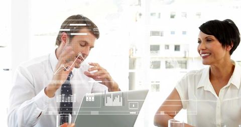 Business professionals discussing analytics dashboard on laptop in modern meeting room