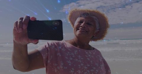 Elderly Woman Enjoys Happiness at Beachside with Smartphone Selfie