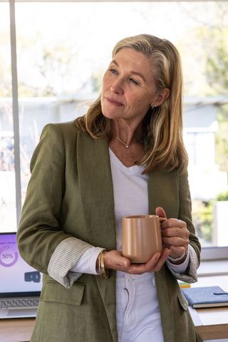 Senior Woman in Home Office Holding Mug, Relaxed and Contemplative