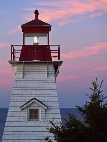 Vintage white lighthouse against pink and blue twilight sky