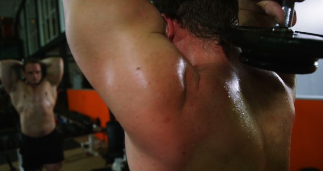 Close-up view of male bodybuilders' muscles during an intense weightlifting session in a gym. Ideal for promoting fitness brands, gym facilities, workout programs, personal training services, and muscle building supplements.