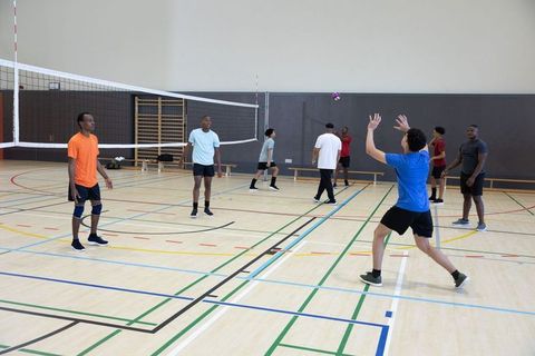 Young african american men playing indoor volleyball during friendly team practice