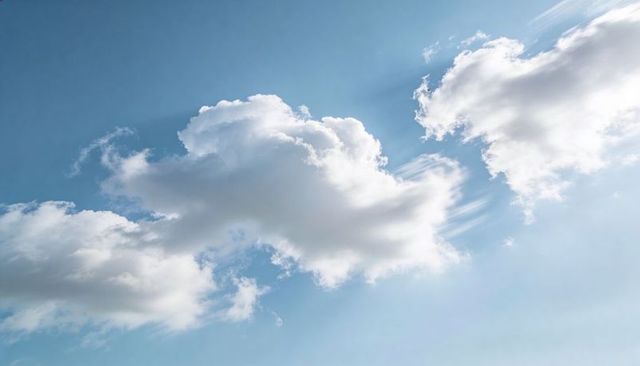 Drifting Sunlit Cumulus Clouds Over Clear Blue Sky Creating Serene Minimalist Atmosphere