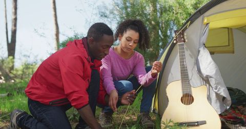 Couple Setting Up Tent Outdoors with Guitar Nearby