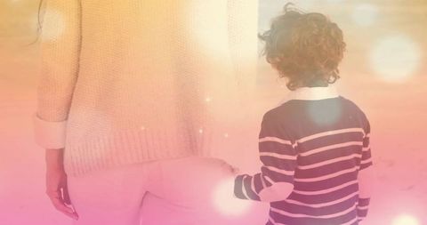 Woman and boy holding hands backlit warm cozy family moment with soft bokeh light and pastel glow