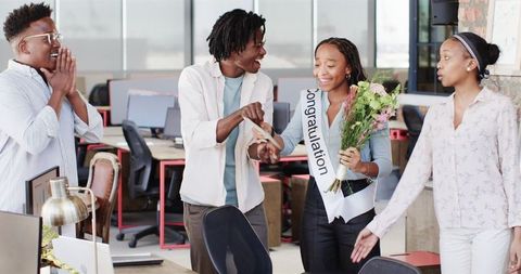 Colleagues celebrating achievement with flowers in office